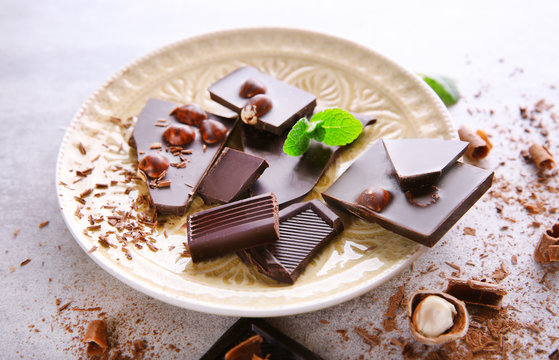 Broken black chocolate with hazelnuts and fresh mint on a plate