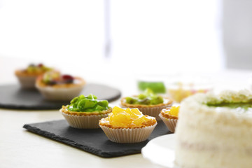 Fresh homemade fruit tarts  and cake on white wooden table.