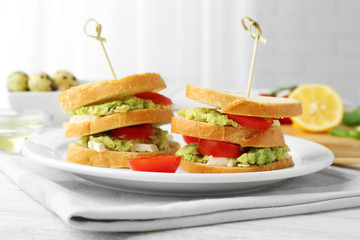 Vegetarian avocado sandwich on a white plate.