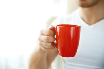 Man holding red cup of coffee in hand, close up