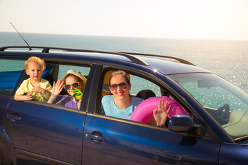 Mother with two kids travel by car on sea vacation