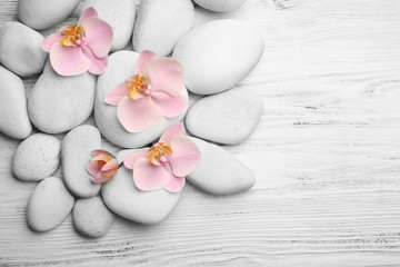 Spa stones and orchid flowers on wooden background