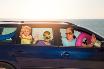 Mother with two kids travel by car on sea vacation