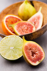Mixed citrus fruit figs, limes on a gray background.