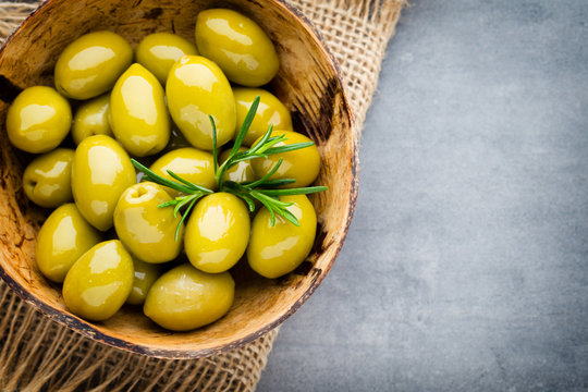 Fresh olives and gray background. Olives in bowl and spoon.