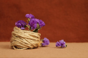 Decorative composition of twine and flowers on a brown background