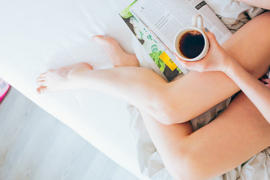 
Junge Frau liegt im Bett und liest Zeitschrift