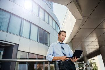 Fototapeta premium Businessman on background of modern building works for the laptop