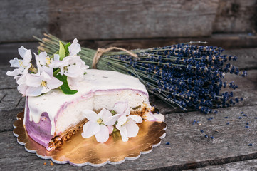 Closeup of the  lavender cheesecake and bouquet with apple flowers on the old planks, section