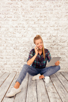 Cheerful cute girl with tablet and cup sitting on the floor talk