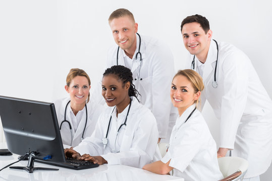 Group Of Doctors Looking At Computer At Desk