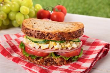 Ham and egg picnic sandwich on summer outdoor table