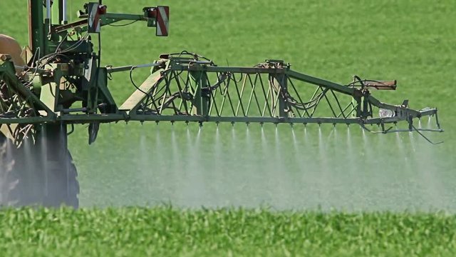 Tractor spraying field, rural landscape in countryside