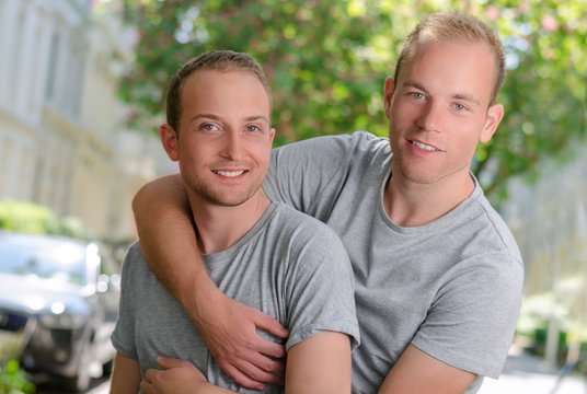 Two homosexual guys on a street. Portrait how they hugging