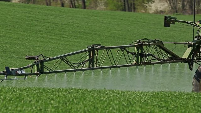 Tractor spraying field, rural landscape in countryside