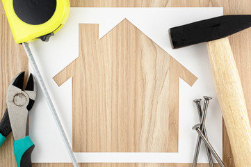 Home planning and preparing.
House shaped paper cutout and tools on wood lumber.