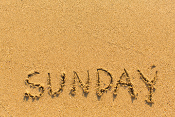 Sunday - inscription by hand on a light-golden beach sand.