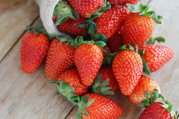 strawberries in small sack on wooden table background