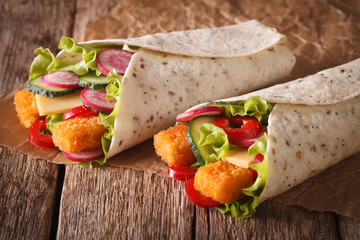 Sandwich roll with fishfingers, cheese and vegetables close-up. horizontal
