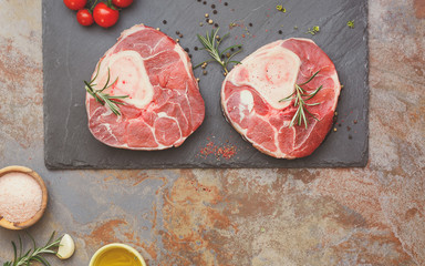 Raw veal knuckles. Freshly sliced veal knuckles on slate stone and seasonings for making Osso Buco.