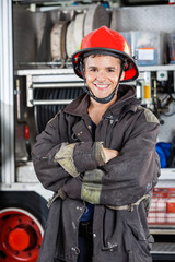 Happy Firefighter Standing Arms Crossed Against Firetruck