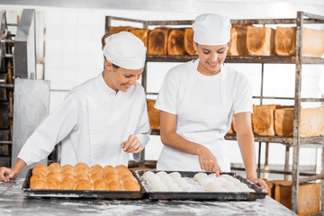 Female Baker's Analyzing Dough At Table