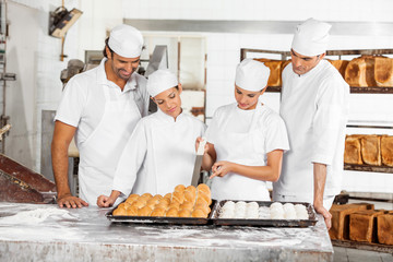 Team Of Baker's Analyzing Breads At Table