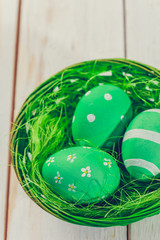 Easter eggs painted in pastel colors on white wooden background.
