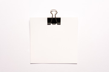 White note paper and black paperclip