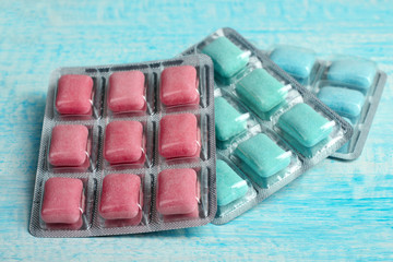 a pack of chewing gum of different colors in form of cushions on blue wooden background