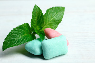 blue and red gum in the form of cushions on white wooden background with mint leaves © Studio KIVI
