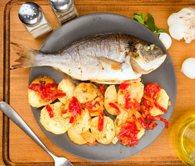 Vertical making roasted sea bream with potatoes on wooden