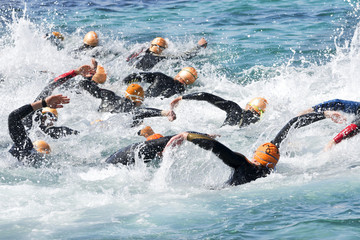 triathlon participants in swim portion of race , selective focus