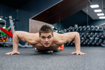 Fototapeta na wymiar young muscular shirtless man doing exercises in gym