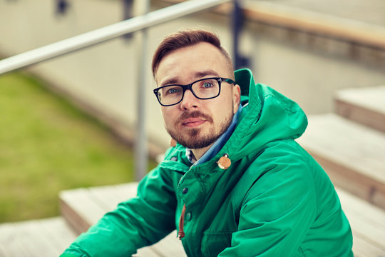 happy young hipster man sitting on stairs in city
