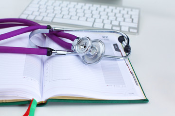 Stethoscope lying on a notebook computer in the background and books