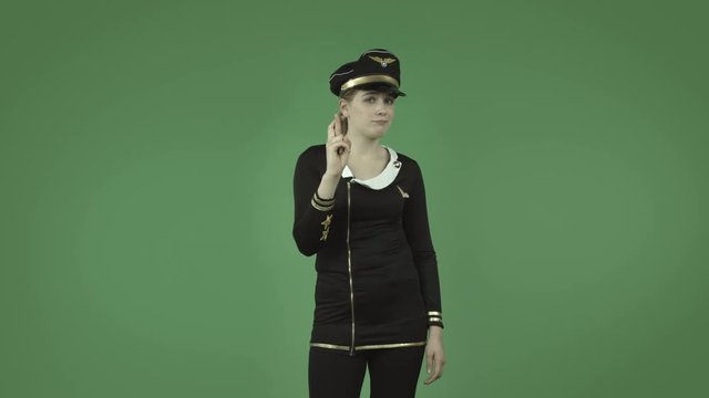 attractive caucasian air hostess isolated on green with fingers crossed