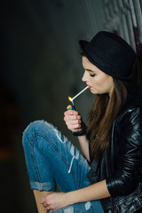 Fototapeta premium Young girl sitting on the floor and smoke