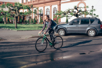 Fototapeta premium young brunette man riding fixed-gear bicycle in the city on a sunny day