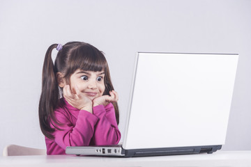 Cute little girl having fun using a laptop computer. Education, technology and e-learning concept