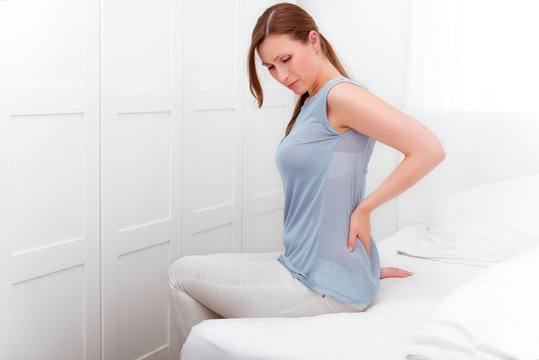 Frau im Bett mit Rückenschmerzen