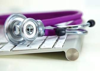 Silver stethoscope lying down on an laptop, toned blue