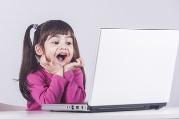 Cute little girl having fun using a laptop computer. Education, technology and e-learning concept