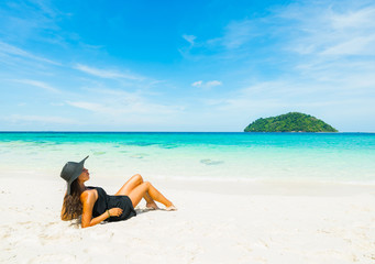 Fototapeta na wymiar Tropical vacation. Young beautiful woman in black dress and hat on the beach. Thailand, Koh Lipe