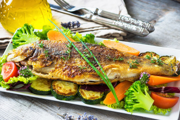 Grilled trout with vegetables on wooden background