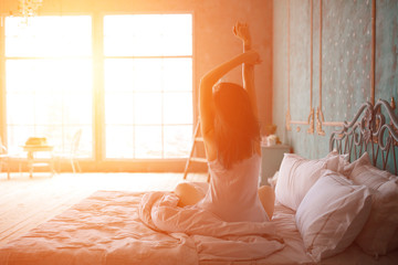 Woman stretching in bed after wake up - obrazy, fototapety, plakaty
