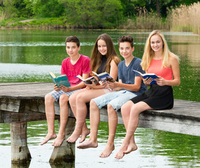 Gruppe Teenager lesen draußen ein Buch