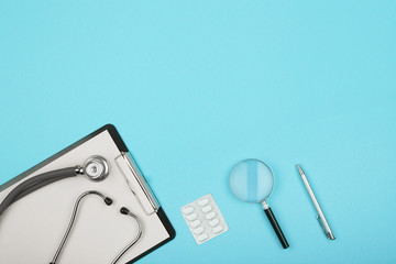 doctors workplace - medical tablet, stethoscope, pills and magnifying glass