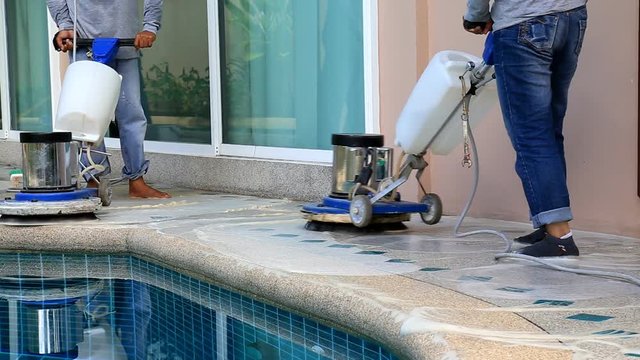 Worker cleaning stone floor with machine and chemical