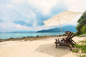 Beach chairs with parasol on the beach in the island in cloudy day